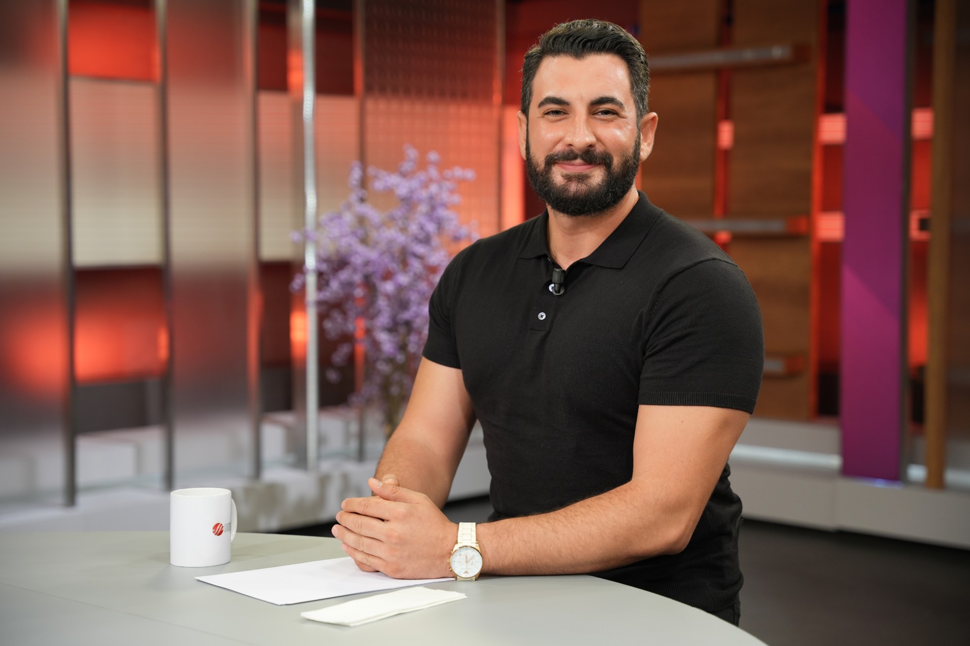 Psikolog Yusuf Efe Göçer stüdyoda masa başında gülümsüyor